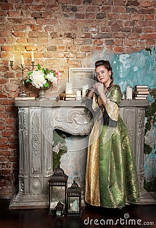 Beautiful woman in medieval dress near fireplace