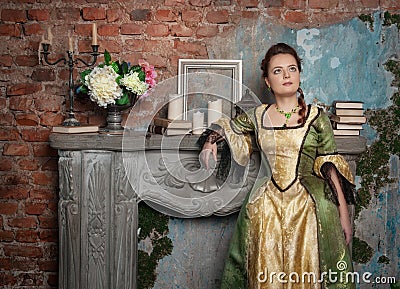 Beautiful woman in medieval dress near fireplace