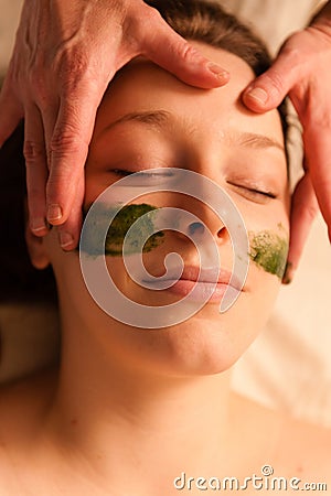 Beautiful woman receiving a facial massage in a spa.