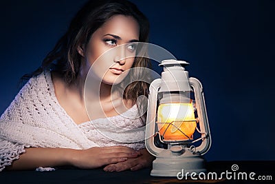 Beautiful woman sitting with lantern over dark
