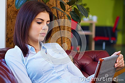 Beautiful woman sitting on the sofa at office and reading