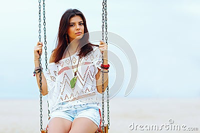 Beautiful woman sitting on a swing on the beach