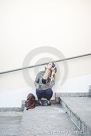 Beautiful young blonde hipster woman listening music