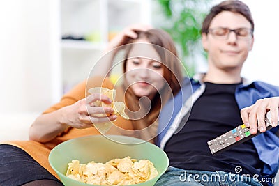 Beautiful young couple watching tv and eating on a sofa