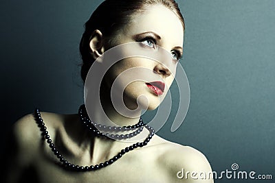The beautiful young girl with a dark blue beads on a neck