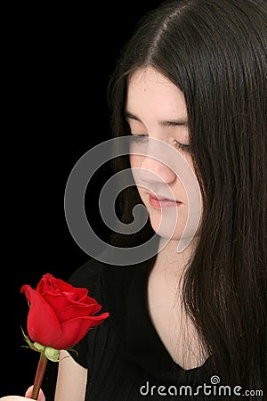 Beautiful Young Girl Looking At Red Rose Against Black