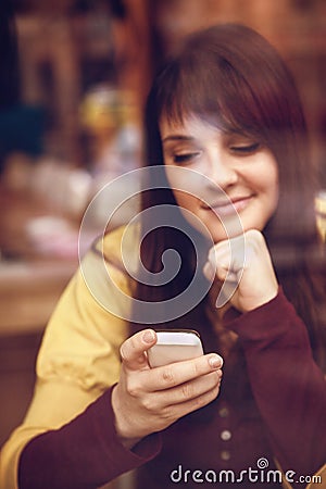 Beautiful young girl using smart phone in a cafe