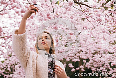 Beautiful young lady photographing nature with her mobile phone