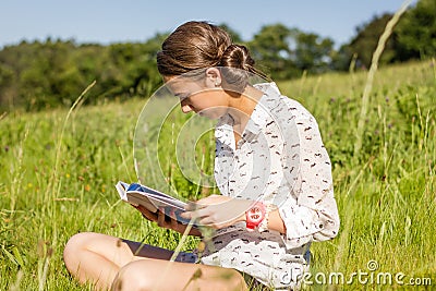 Beautiful young student reading a book in the park