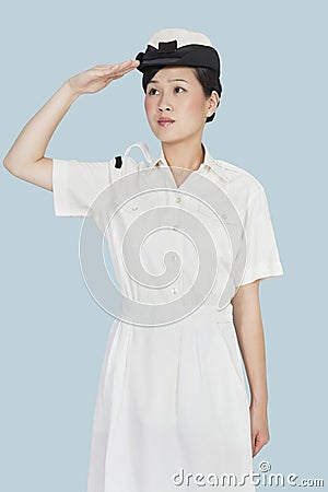 Beautiful young US Navy officer saluting over light blue background