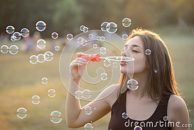 Beautiful Young Woman Blowing Bubbles Outside