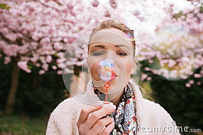 Beautiful young woman blowing bubbles at park