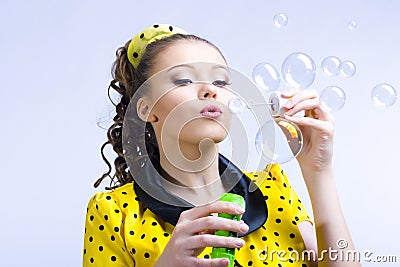 Beautiful young woman blowing soap bubbles