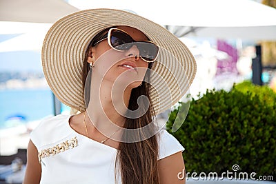 Beautiful young woman in elegant hat and sunglasses