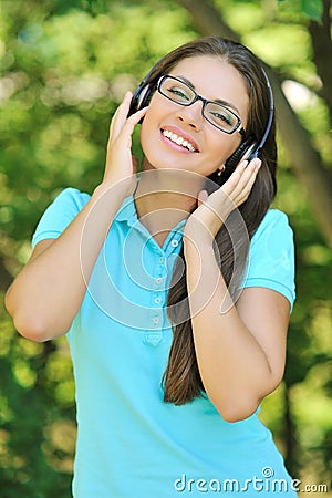 Beautiful young woman with headphones outdoors. Enjoying music