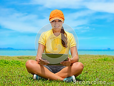 Beautiful young woman on the lawn with her tablet computer