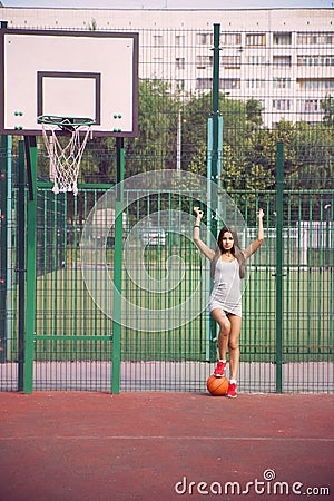 Beautiful young woman playing basketball outdoors