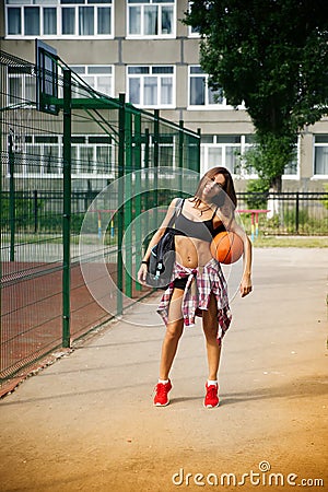 Beautiful young woman playing basketball outdoors