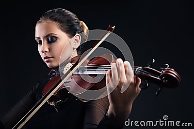 Beautiful young woman playing violin over black