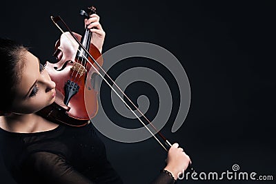 Beautiful young woman playing violin over black