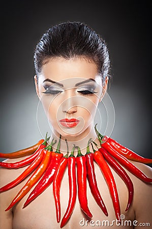 Beautiful young woman portrait with red hot and spicy peppers