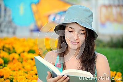 Beautiful young woman reading a book outside