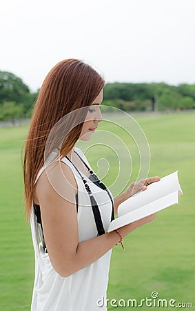 Beautiful young woman reading outdoors