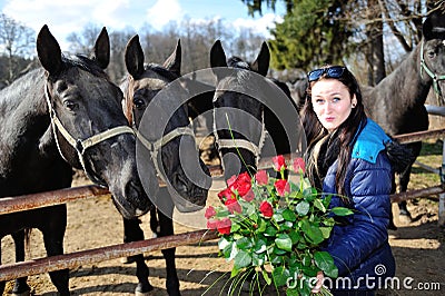 Beautiful young woman with roses and black horses