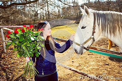 Beautiful young woman with roses and white horse