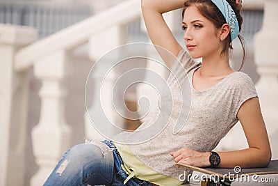 Beautiful young woman with skateboard in city