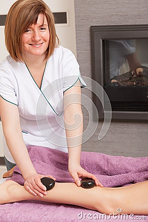 Beauty salon. Woman getting spa hot stone legs massage