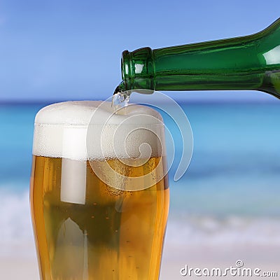 Beer pouring from bottle into glass on beach and sea