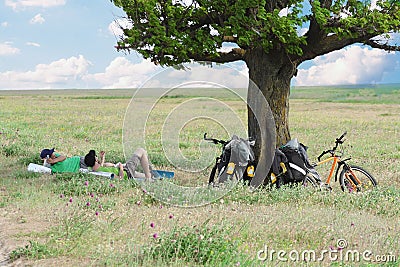Bicycle tourists resting near tree