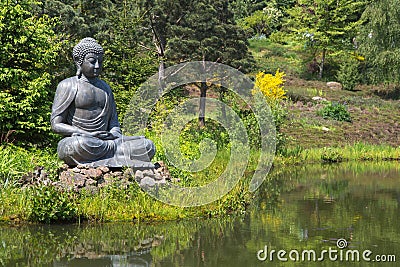 Big buddha statue next to the garden pond.