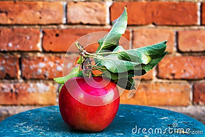 Big Ripe Red Apple with green leaves on vintage wooden table. F