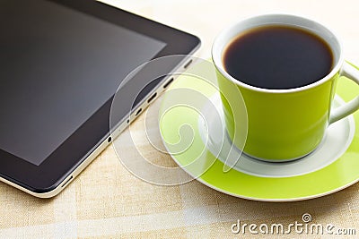 Black coffee in green cup with computer tablet