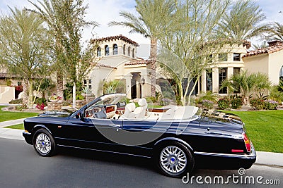 Black convertible car parked in front f luxury house