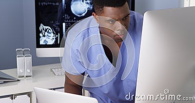 Black doctor working on multiple computers