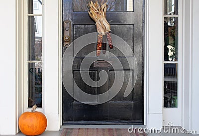 Black door with indian corn and fall pumpkin