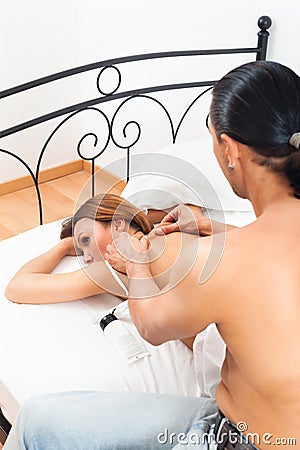 Black-haired man massaging his wife