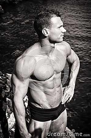 Black and white photo of attractive muscular young man by the sea