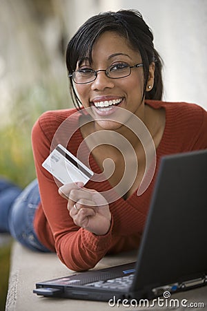 Black woman using credit card and laptop outside
