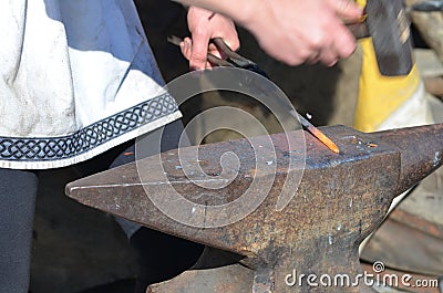 Blacksmith hammers red hot iron on an anvil