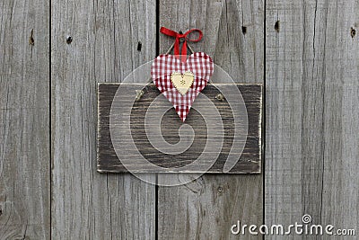 Blank wooden sign with red gingham and gold hearts hanging on wood background