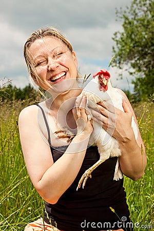 Blond beautiful woman hugs an white chicken
