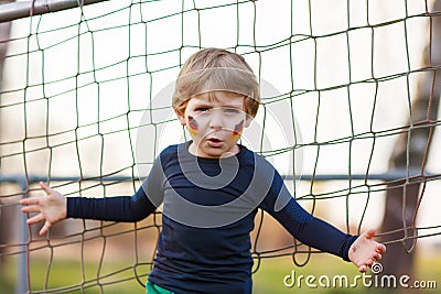 Blond boy of 4 playing soccer with football on football field