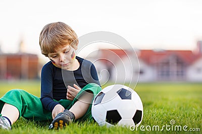 Blond boy of 4 playing soccer with football on football field