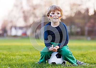 Blond boy of 4 playing soccer with football on football field