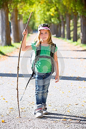 Blond explorer kid girl walking with backpack in autumn trees