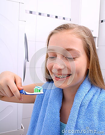 Blond girl with braces smiling while brushing your teeth